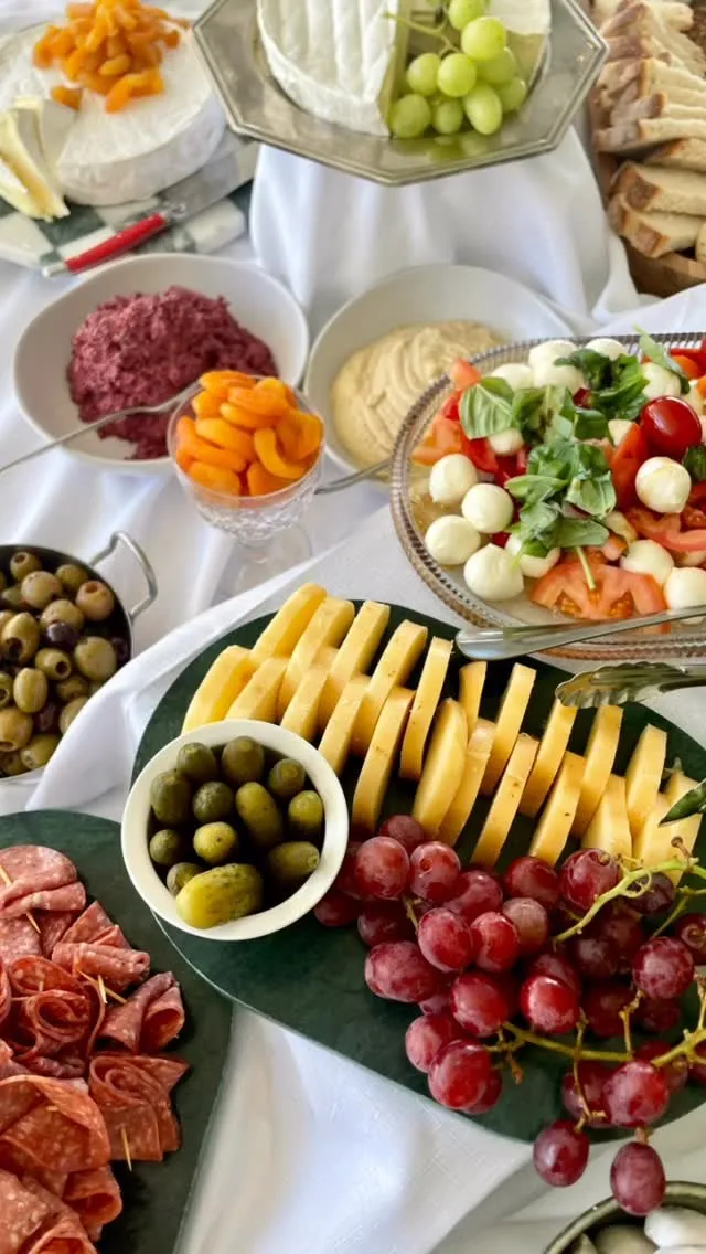 A grazing table with cheeses, fruit, crackers and flowers